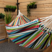A colourful striped hammock suspended in a backyard patio
