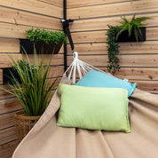 A Sunbrella hammock in Sand styled with two pillows in a backyard patio 