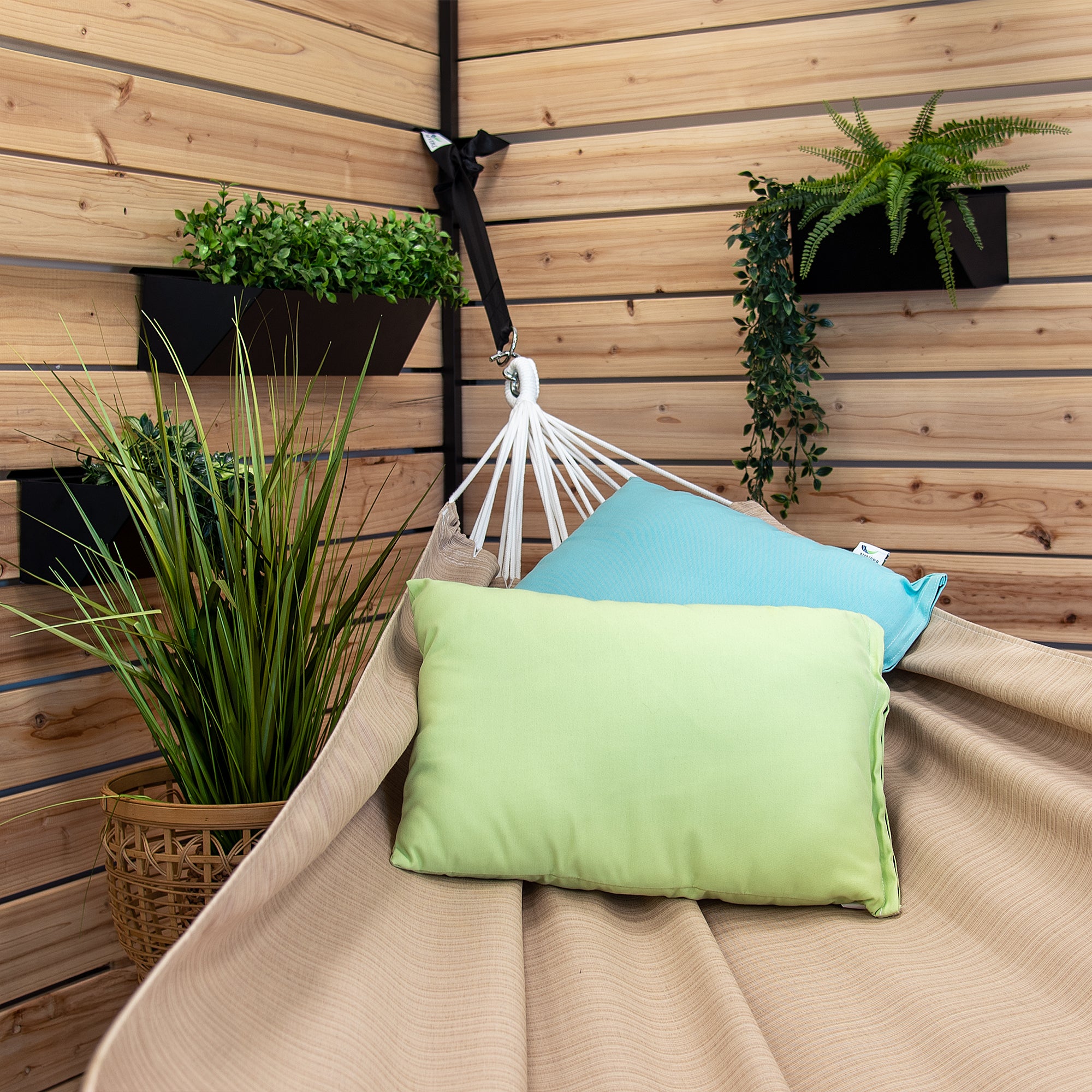 A Sunbrella hammock in Sand styled with two pillows in a backyard patio 